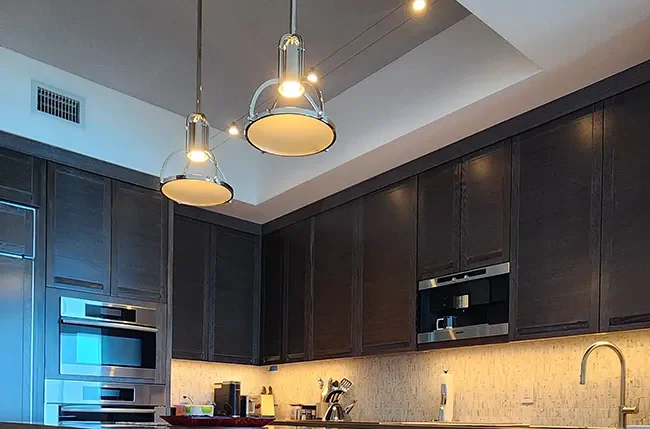 Pendant lights and warm under-cabinet lighting in a kitchen