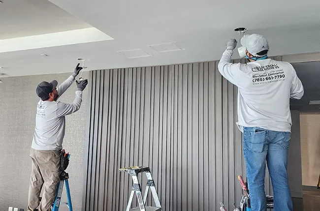 Two Electrical Solution US technicians installing fixtures in a condo