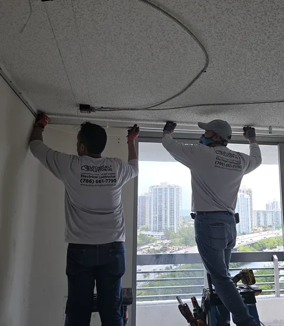 Two technicians installing the perimeter frame of a ceiling