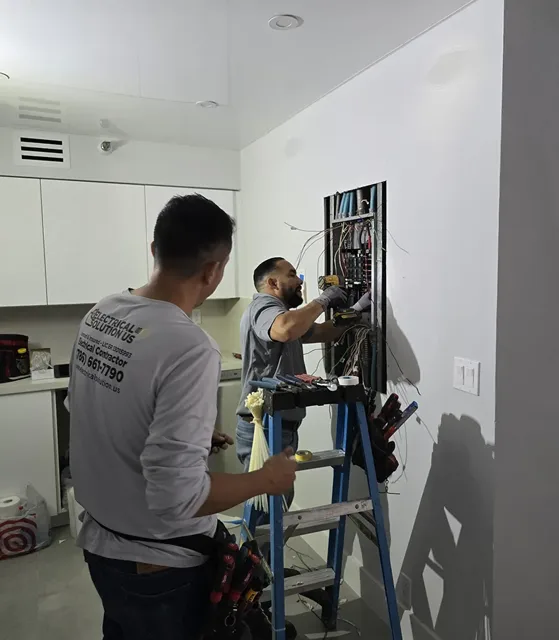 Two technicians working on an open electrical panel