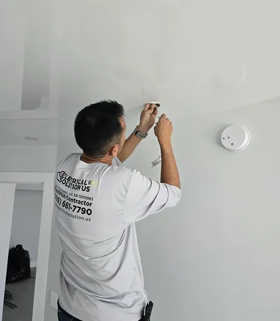 Technician installing a wall-mounted electrical device